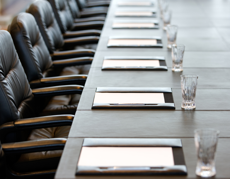 paper on table at a board meeting with empty chairs and empty water glasses