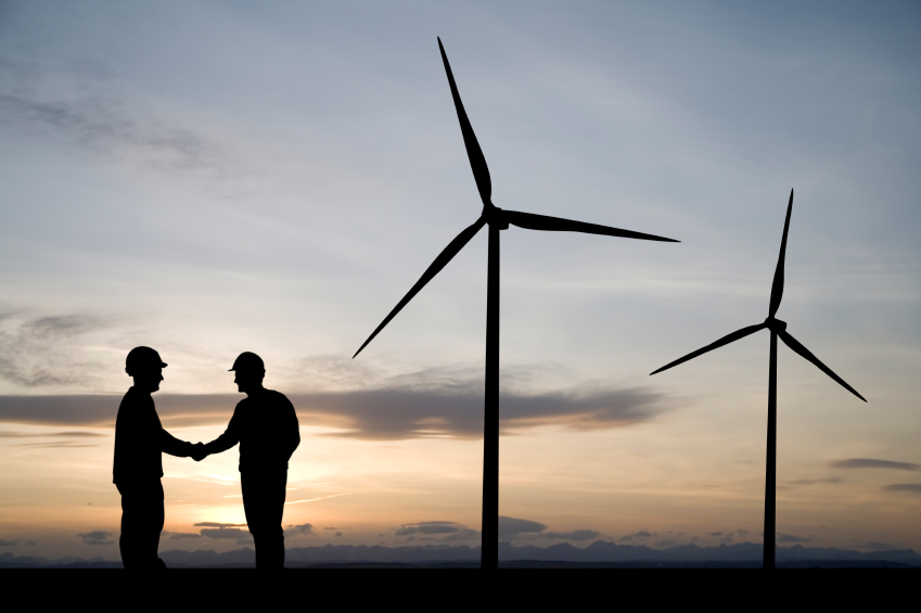 handshake between two farmers in front of two wind turbines
