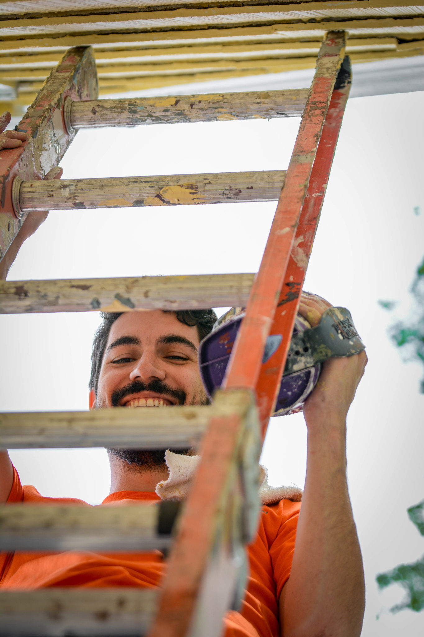 a man is smiling while standing on a ladder