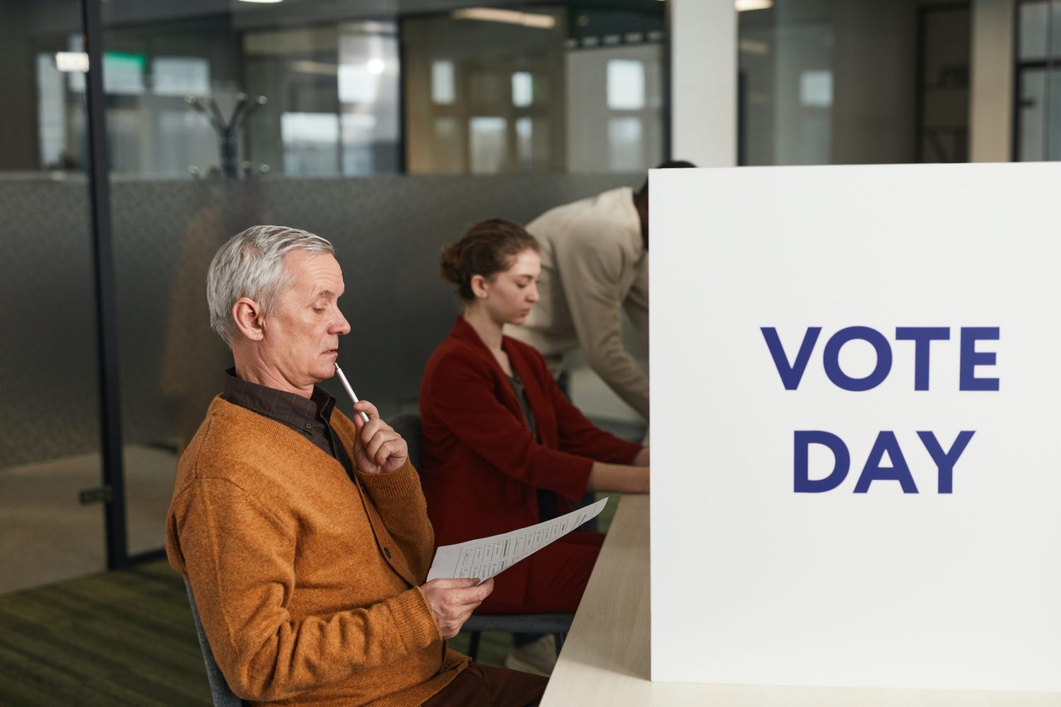 a man sits in front of a sign that says vote day