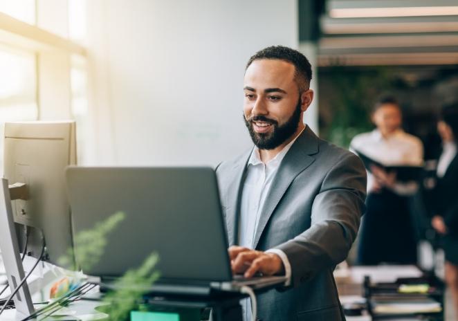 a man in a suit is typing on a laptop